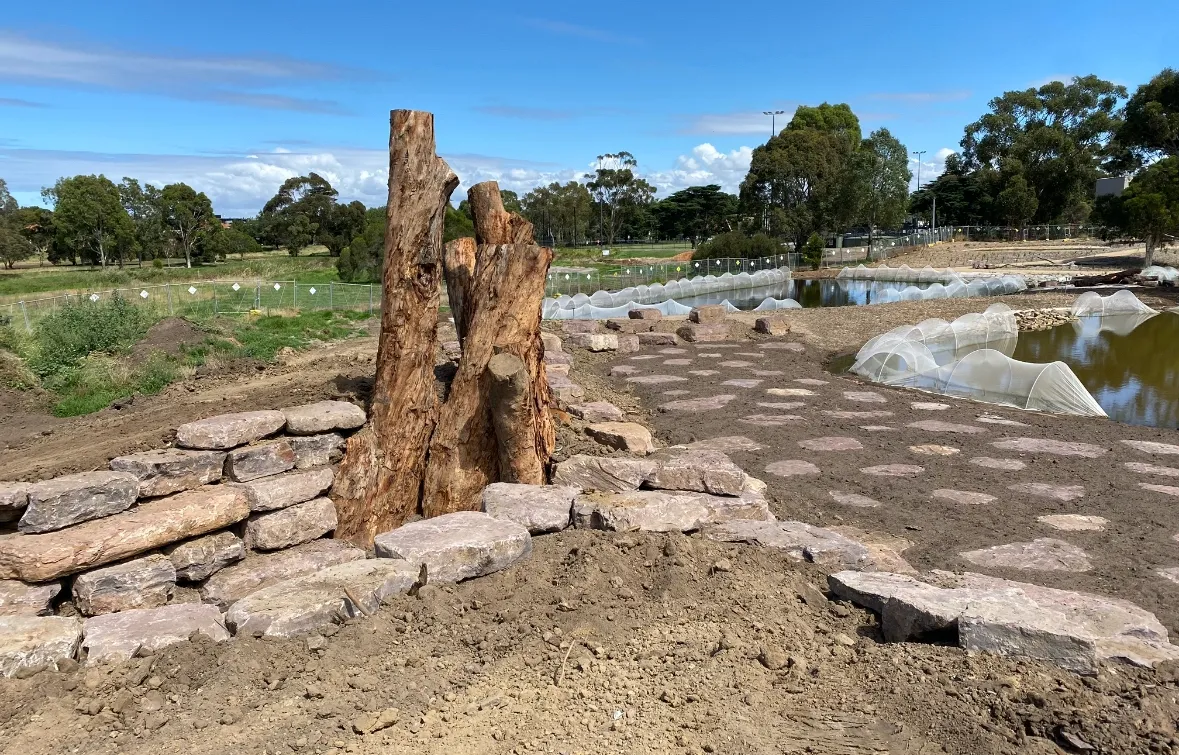 Outdoor area with trees and stone structures.