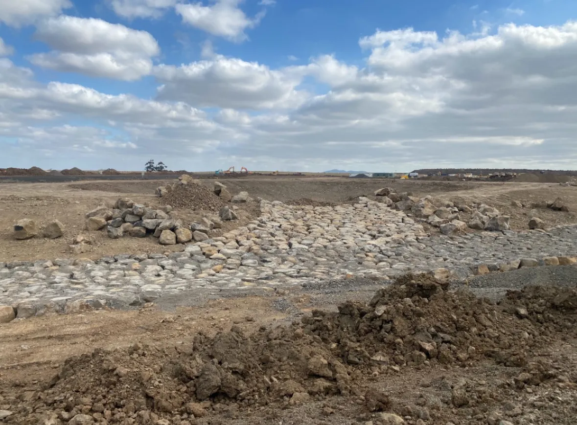 Rocky construction site under cloudy sky.