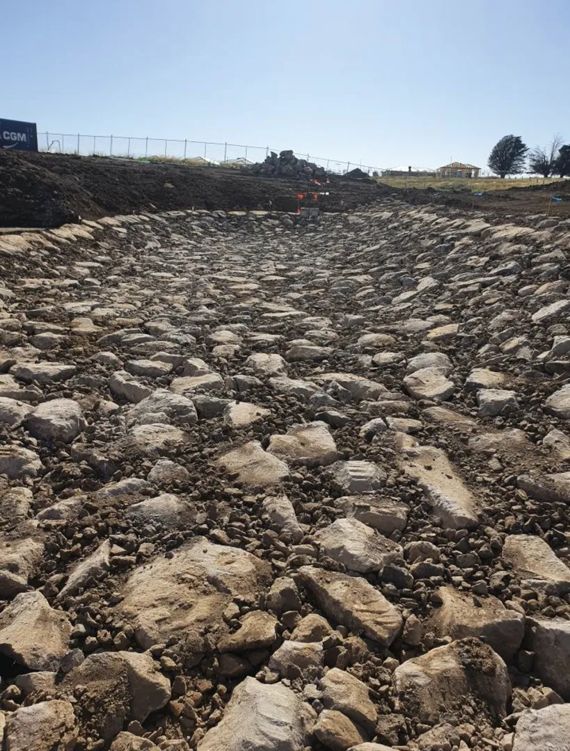 Large trench filled with rocks on a construction site.